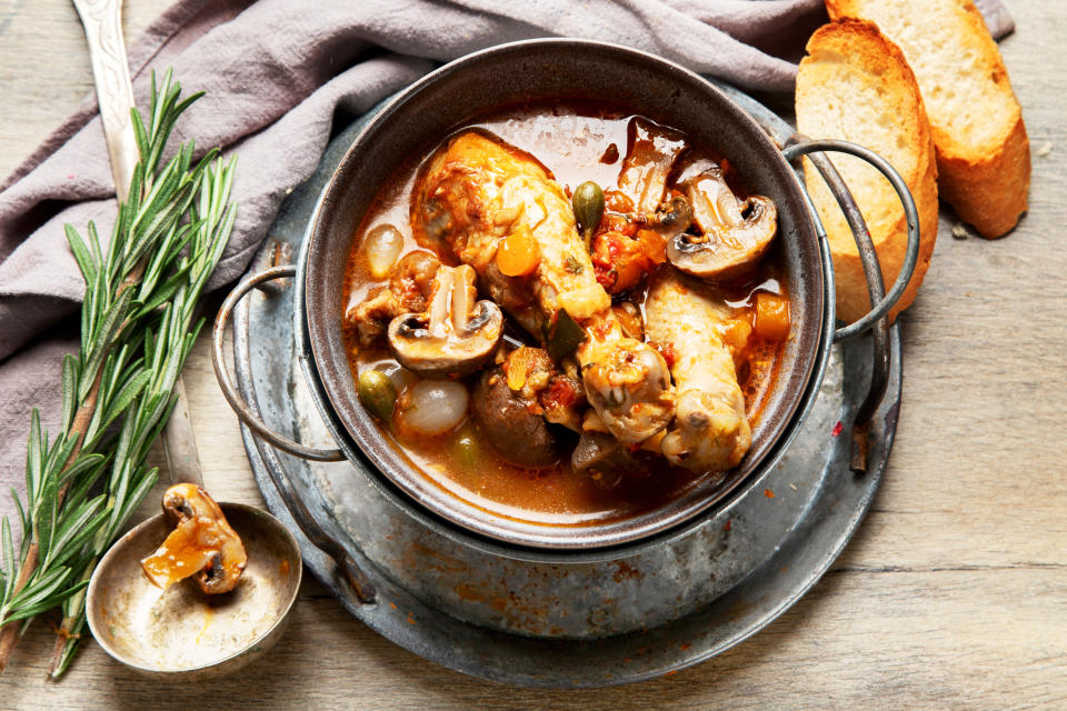 Traditional French coq au vin with vegetable marinated in Burgundy sauce braised with red wine, bacon, mushrooms, and onion on a wooden background. Top view.