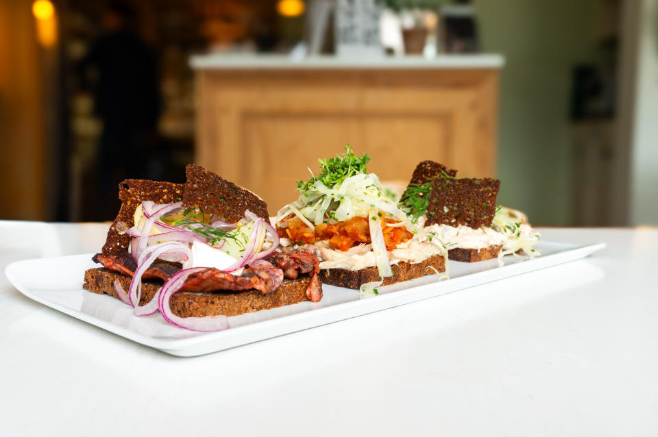 Smorrebrod in a restaurant in Copenhagen, traditional Danish open sanwiches, dark rye bread with different topping, Denmark.