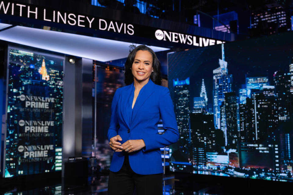 Linsey Davis on an ABC News Live Prime set, wearing a royal blue jacket and black pencil skirt.