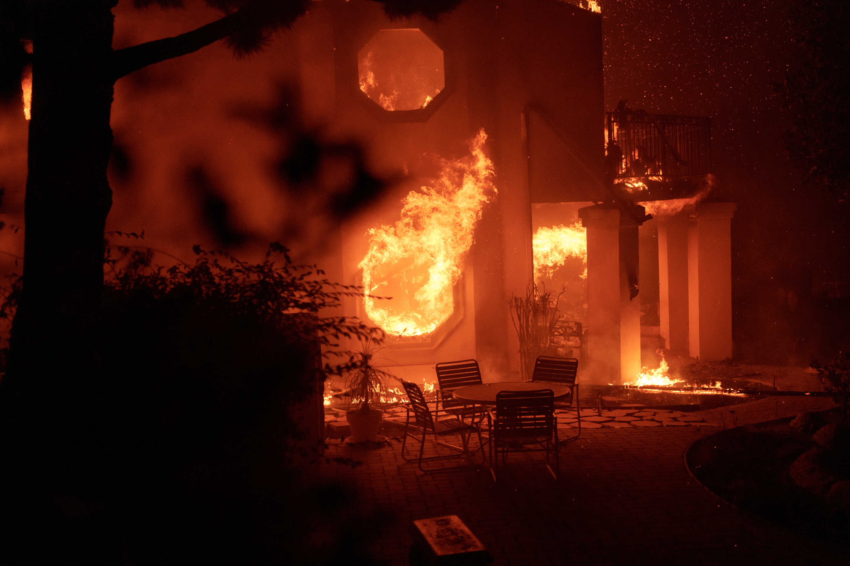 Flames can be seen shooting from the windows of a house engulfed by fire.