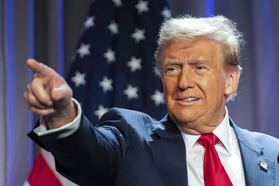 President-elect Donald Trump, with a U.S. flag behind him, points out at his audience.