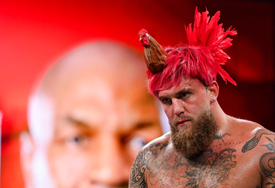 Jake Paul, wearing a rooster hate, during an open workout session in Irving, Texas, USA, ahead of his heavyweight bout with Mike Tyson, whose image is superimposed in the background..