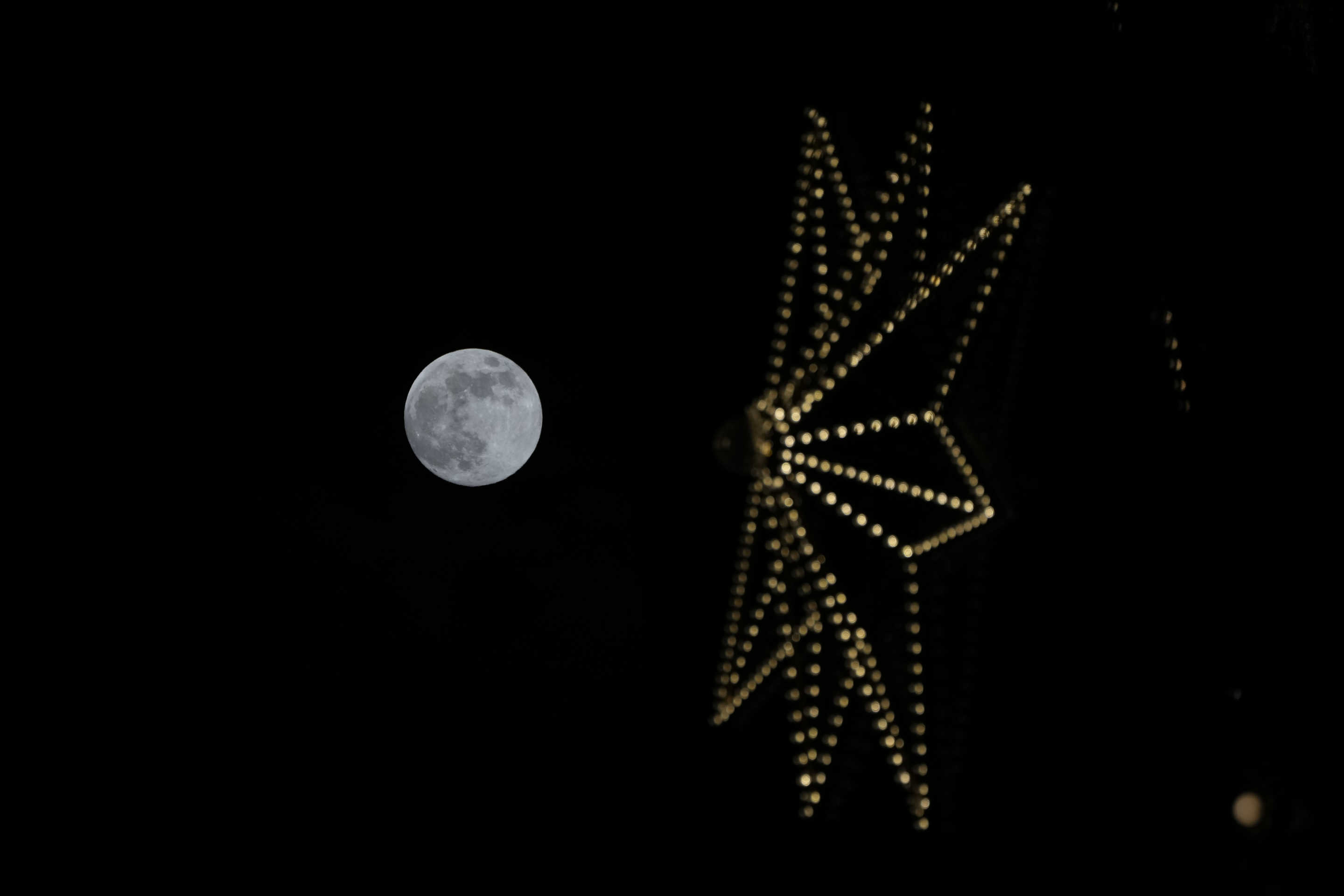 The moon is seen behind a Christmas decoration in Seoul, South Korea, on Friday.