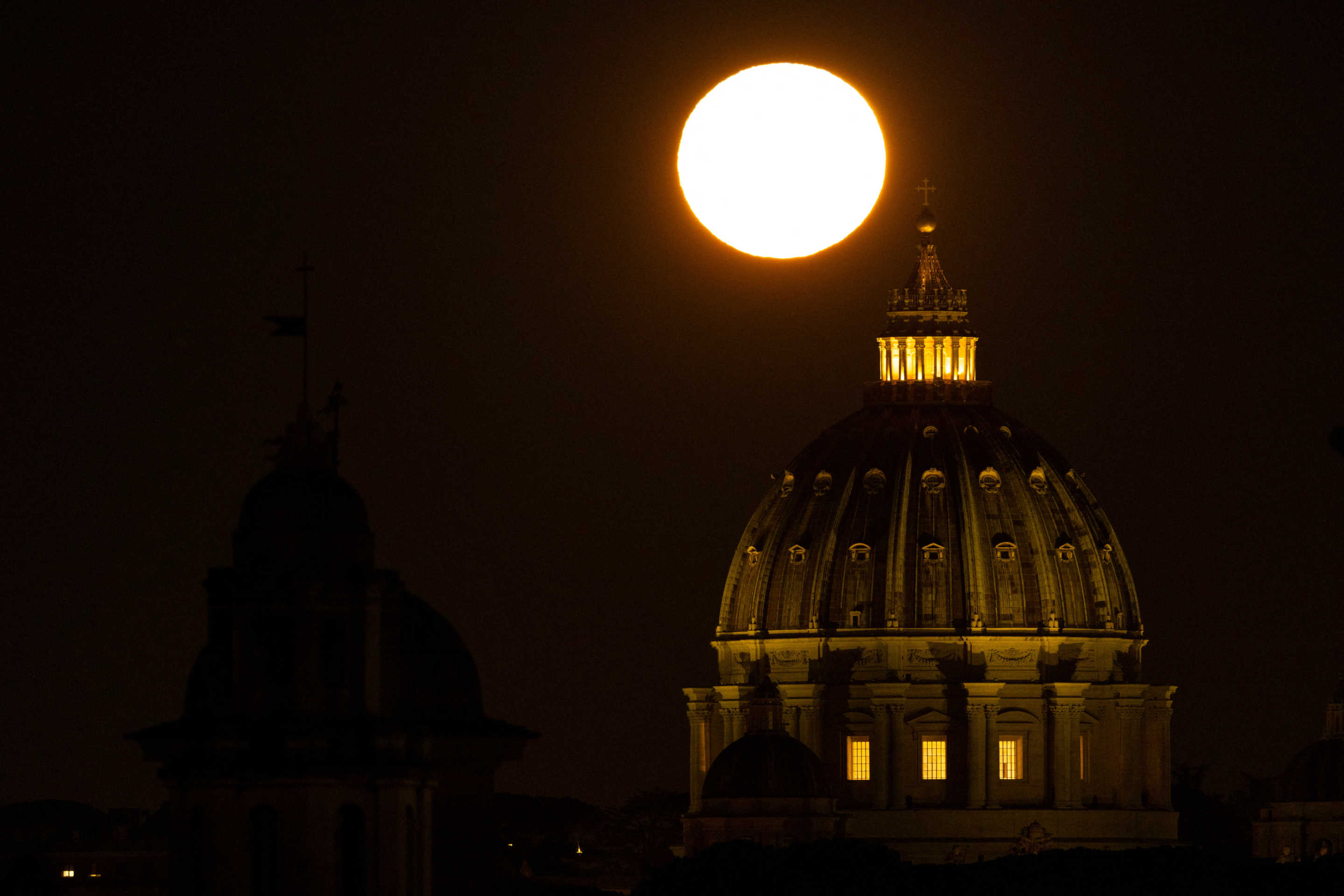 The supermoon sets next the Saint Peter's dome in Rome on Friday.