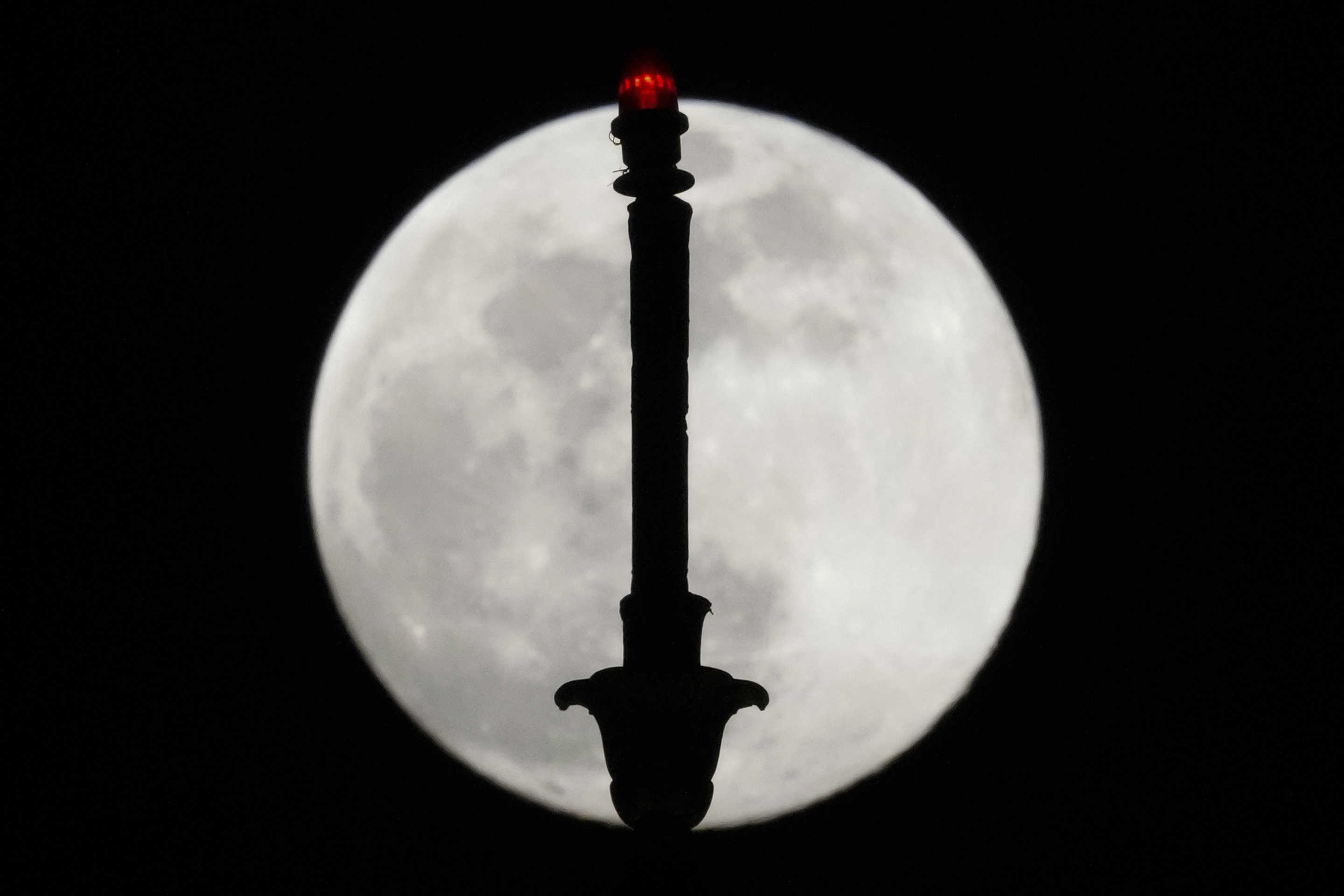 The last supermoon of the year rises behind the city hall clock tower in Manila, Philippines, on Friday. 