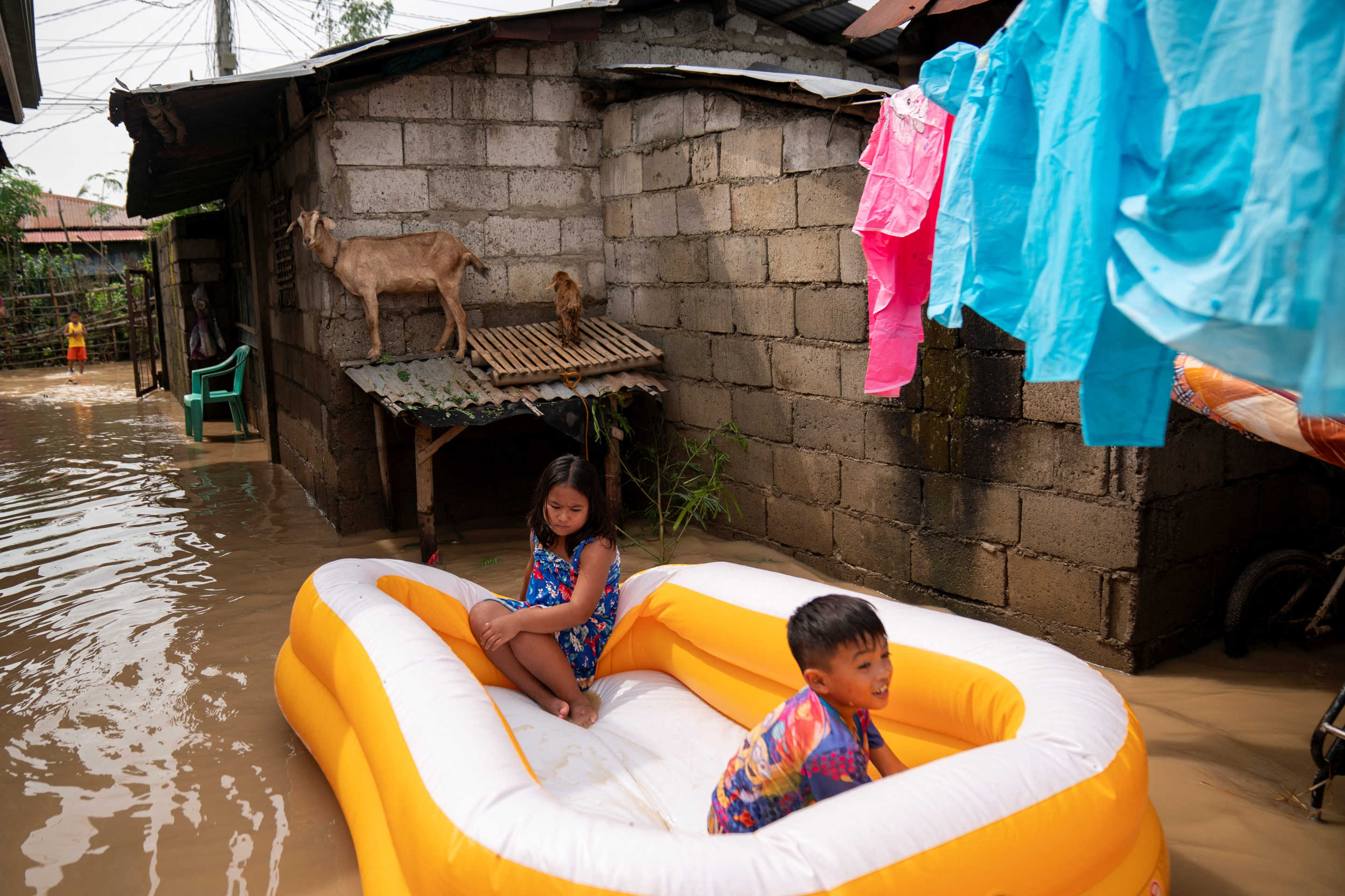 Children sit in an inflatable pool in a flooded alley following typhoon Man-yi, in Quezon town, Nueva Ecija, Philippines.