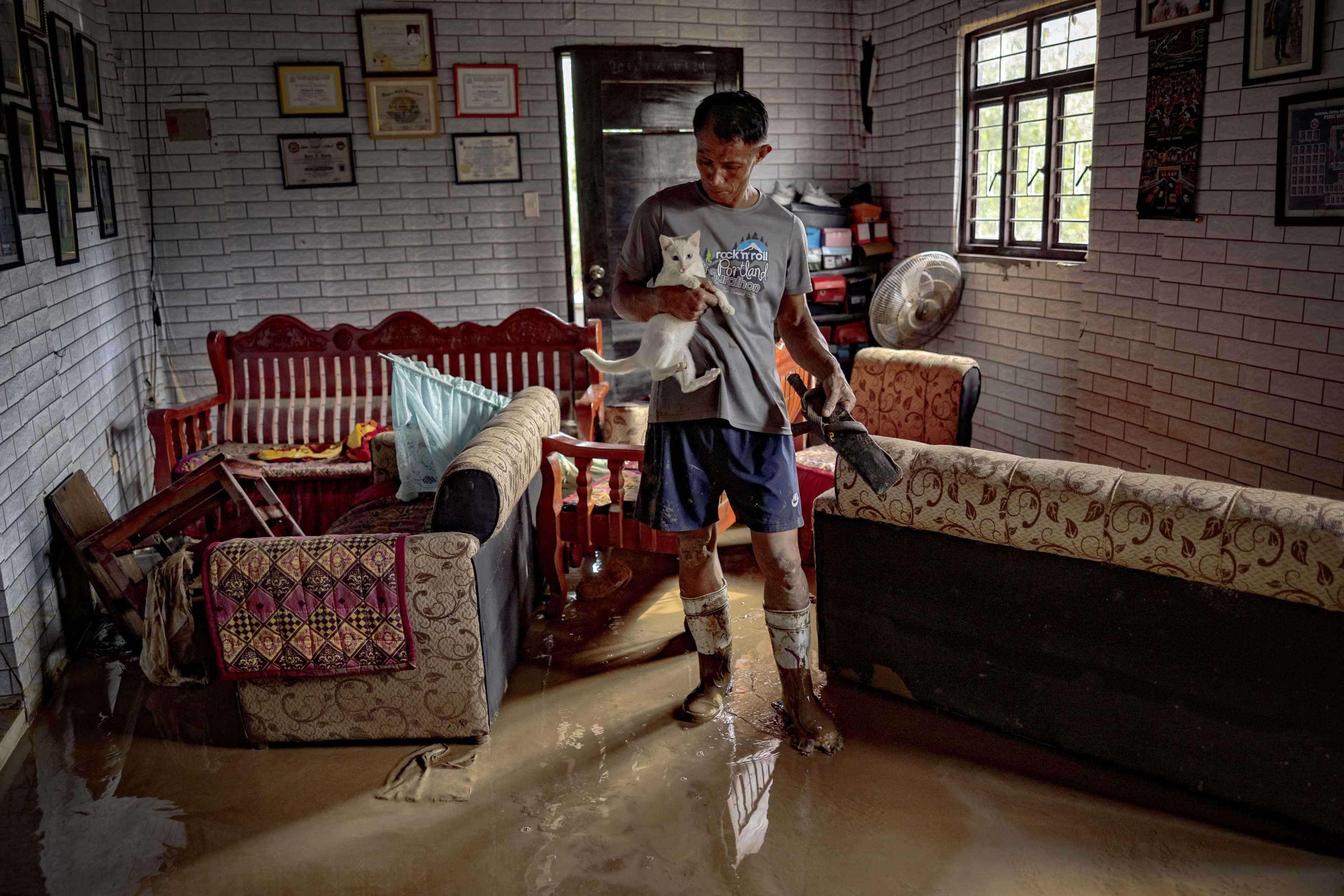 Manuel Lunag Jr. carries his pet cat inside his house that was flooded by Super Typhoon Man-yi in Bayombong.