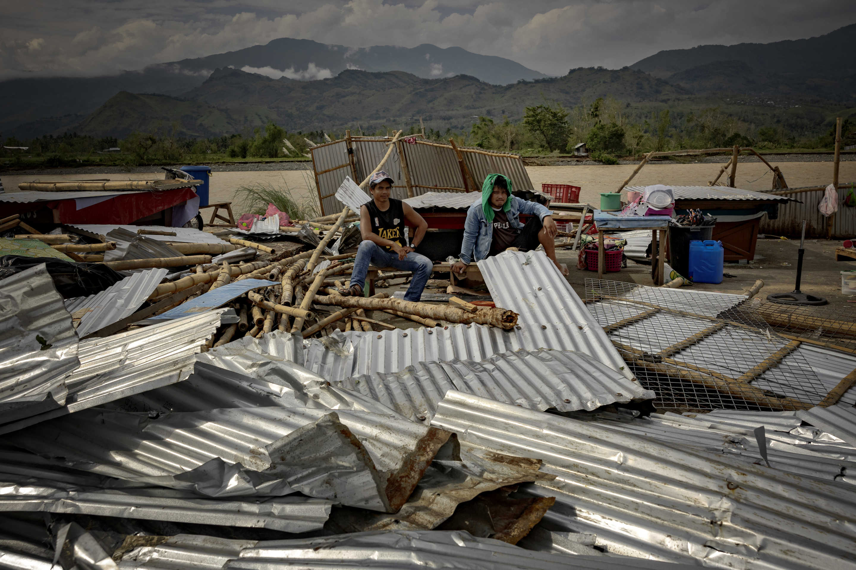 Residents sit next to a collapsed shop after it was destroyed by Super Typhoon Man-yi in Bambang, Nueva Vizcaya province.