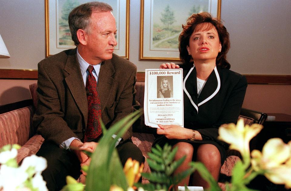 John Ramsey listens as his wife, Patsy, holds up a flyer advertising a $100,000 reward for information leading to arrest of their daughter's killer.