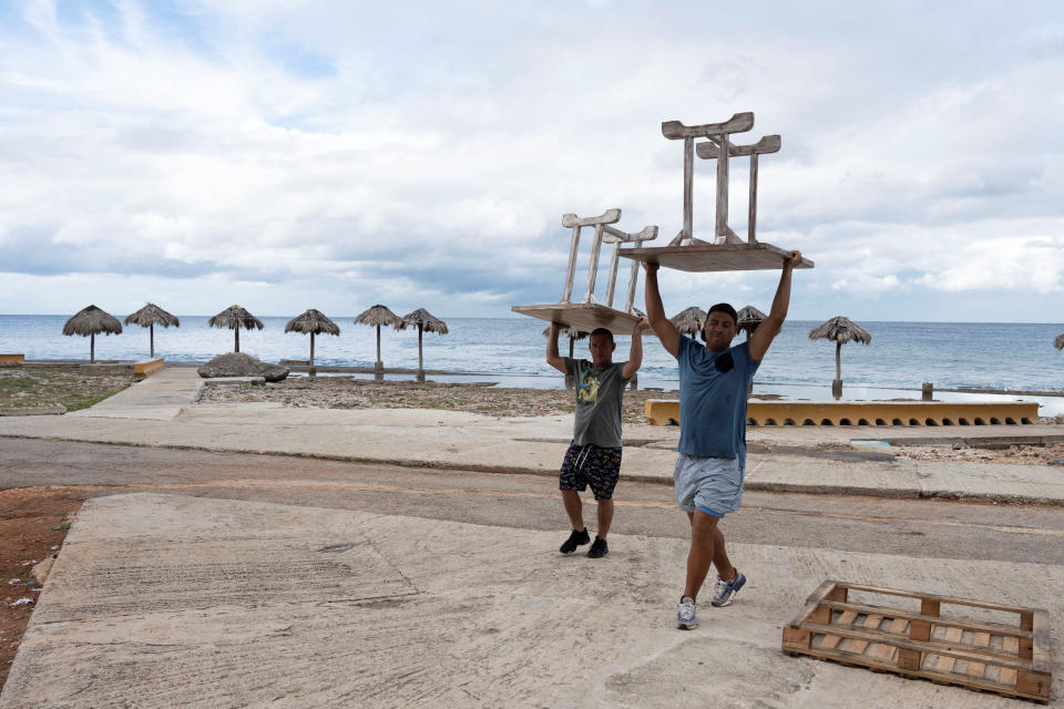 Men relocate furniture from a restaurant prior to the arrival of Tropical Storm Rafael 