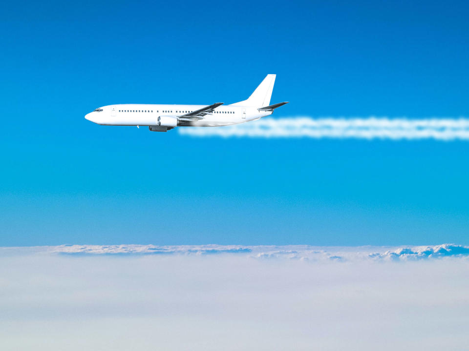 This is a photo of a passenger airplane flying above the clouds, leaving a smoke trail. It is flying at cruising altitude, around 40000 feet.