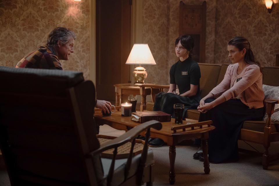 Hugh Grant, Chloe East and Sophie Thatcher sit around a coffee table.