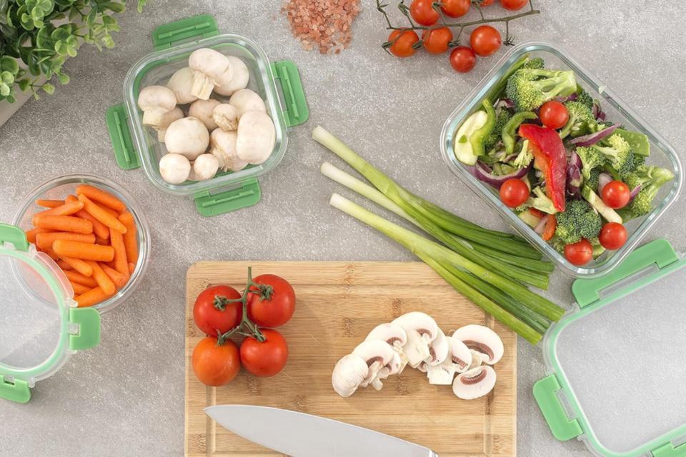 Glass food containers holding vegetables on a kitchen counter.