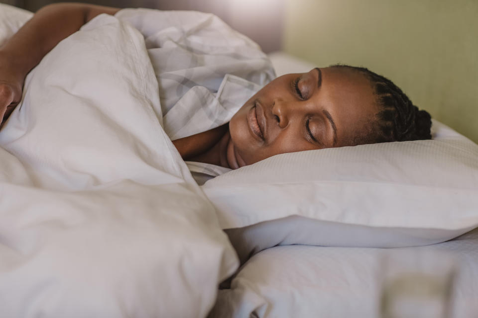 woman sound asleep under a duvet in her bed 