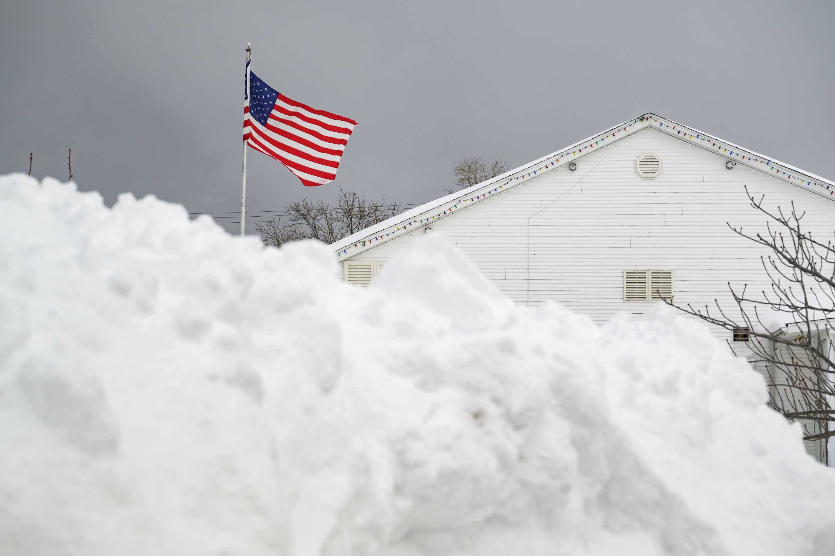 The flag flies over the Lawrence Park Athletic Club after a record snowfall left over 3 feet on the ground, leaving a mountain of snow, which can be seen in the foreground.