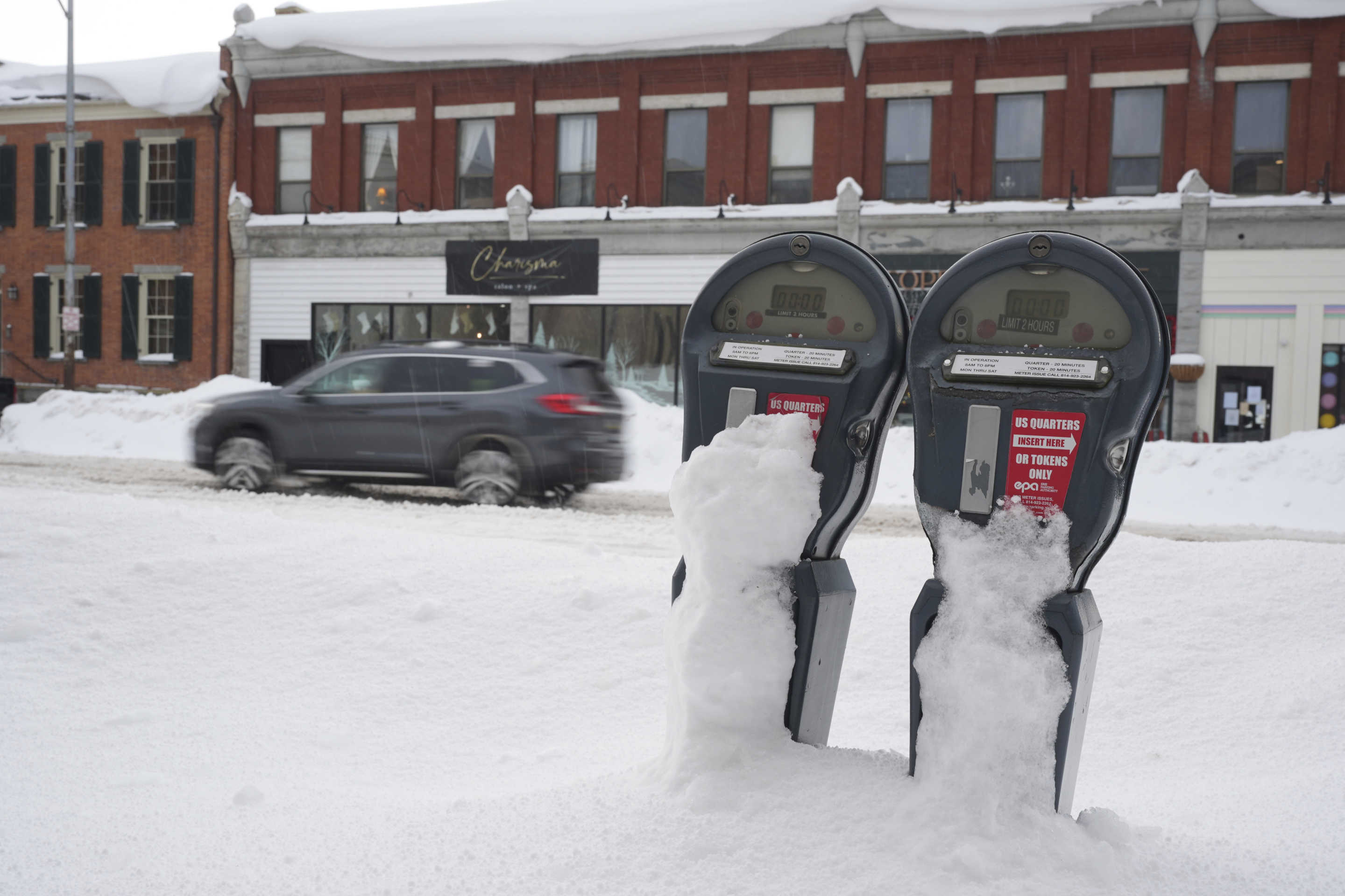 The tops of two buried parking meters can be seen popping out of the snow on Monday on State Street in downtown Erie, Pa.