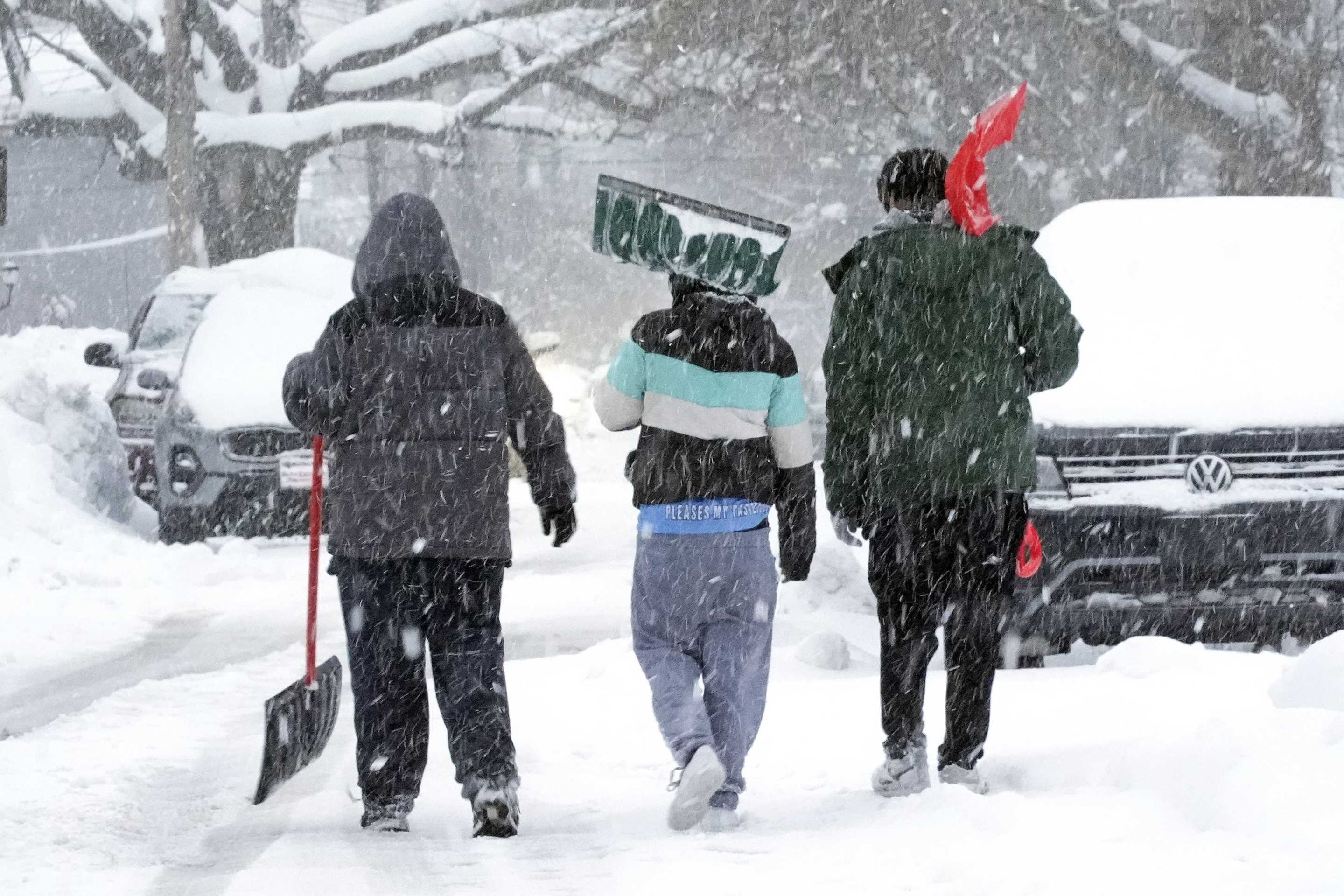 Boys carrying shovels walk down a snow-covered side street in Erie, Pa.