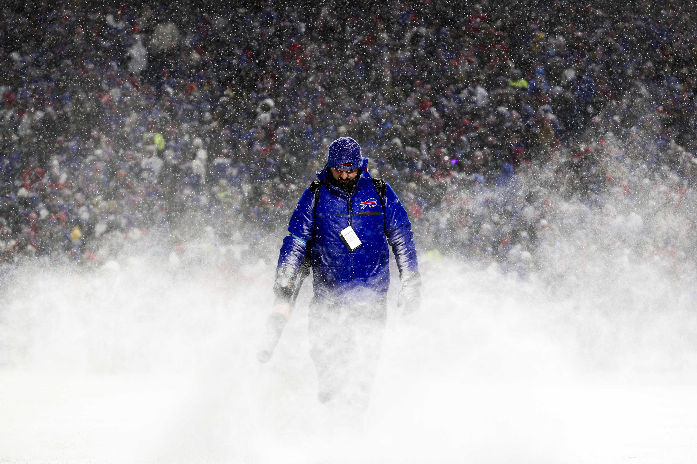 A grounds crew member blows snow off the field at Highmark Stadium.