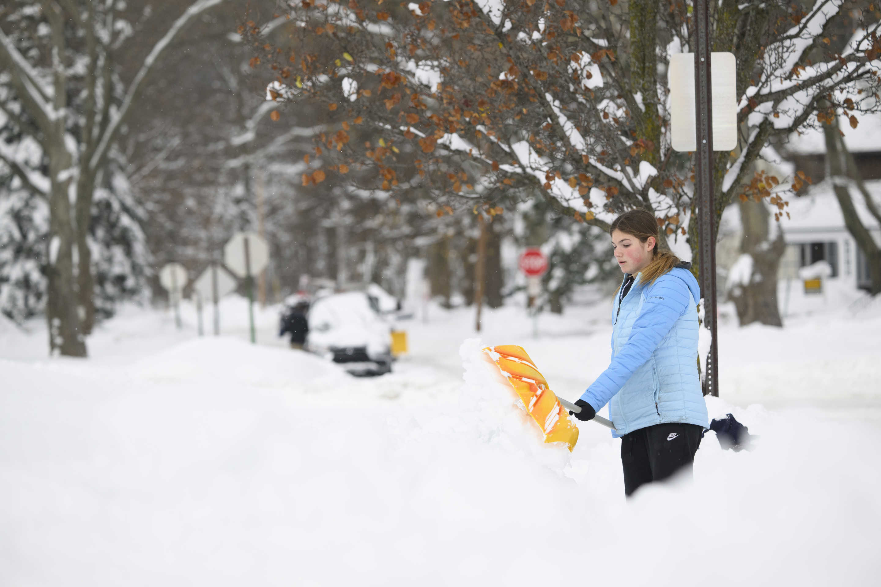 Riley Coblentz, 13, shovels snow from the sidewalk in front of her friend's house after a record snowfall.