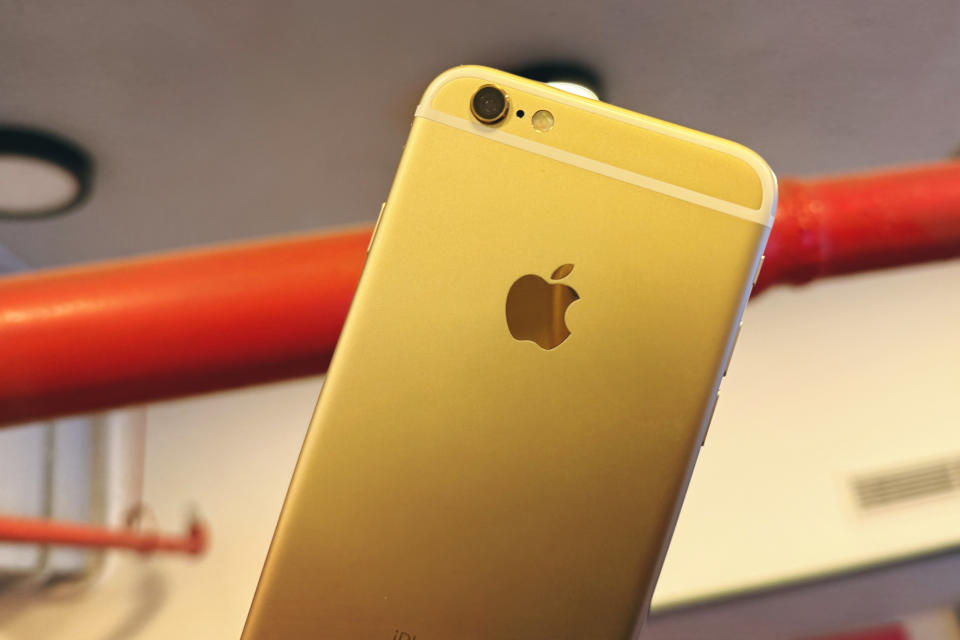 An iPhone 6S in gold held against a red pipe.