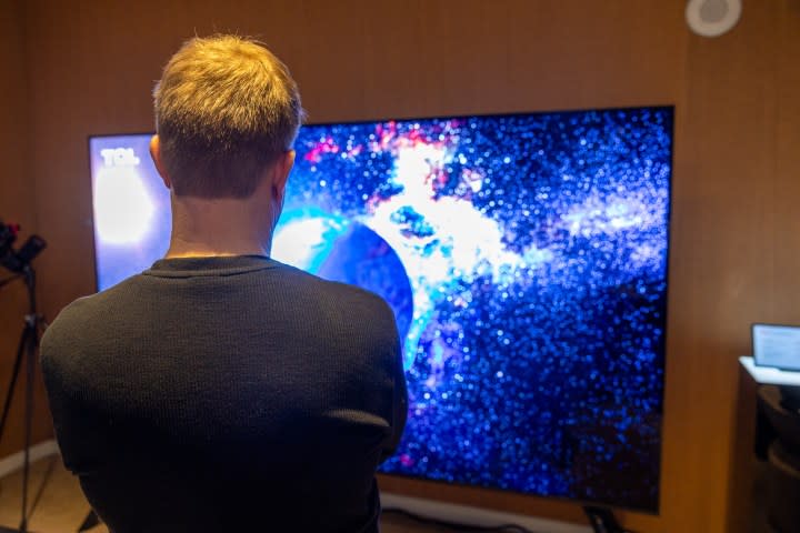 Caleb Denison standing in front of the 115-inch TCL QM89.