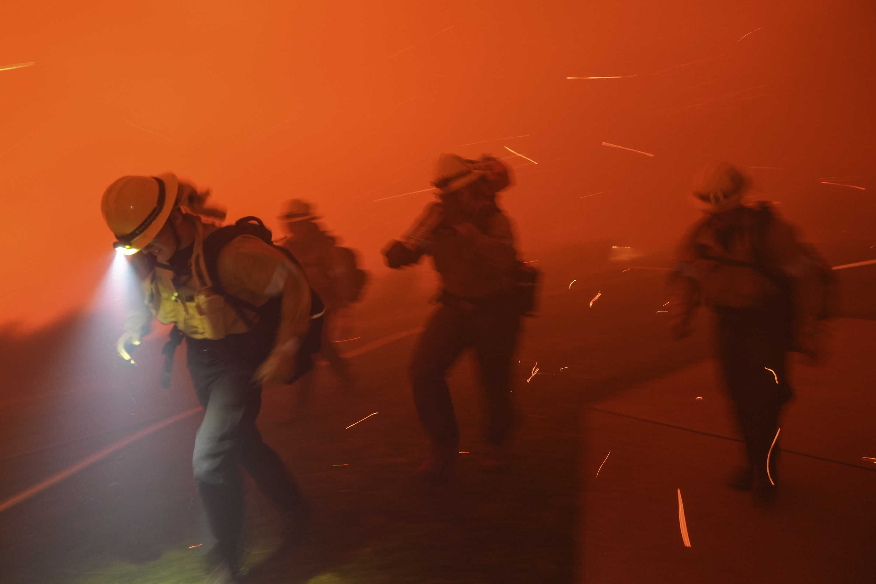 Firefighters are pushed back by strong winds.