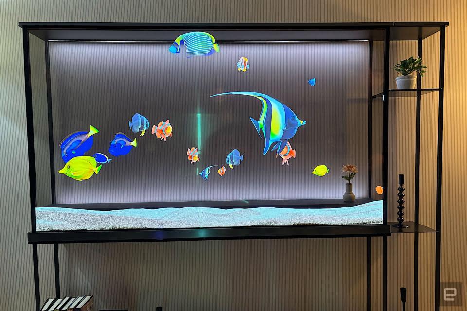 Straight-on view of a transparent OLED TV, showing digital fish swimming in front of the wall, which is visible behind the screen.