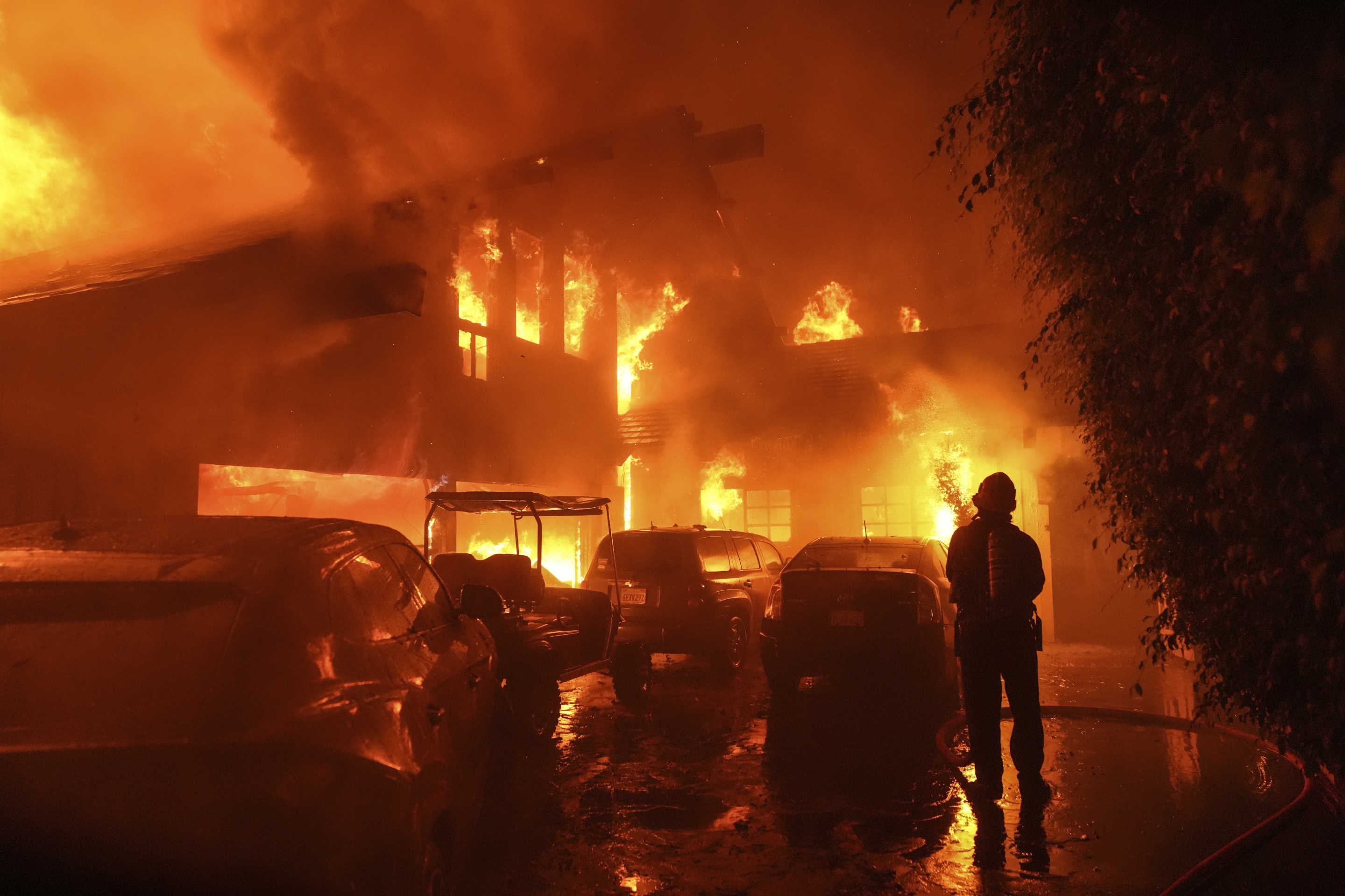 A firefighter hoses a burning home.