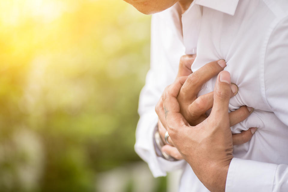 A man seemingly in discomfort holding his hands to his chest.