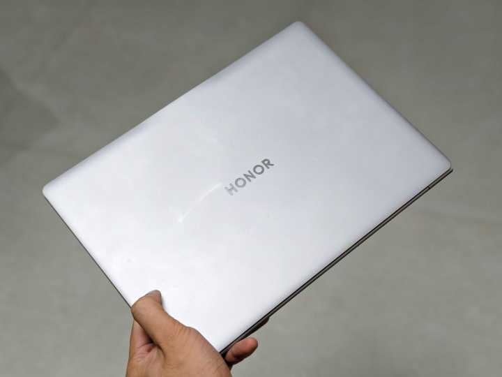 Honor MagicBook Art 14 Snapdragon in hand with lid closed.