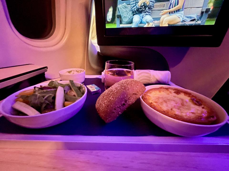 A beautifully plated in-flight dinner on Finnair’s business class, featuring fresh salad, warm bread, and a savory main dish that felt far from standard airplane fare.