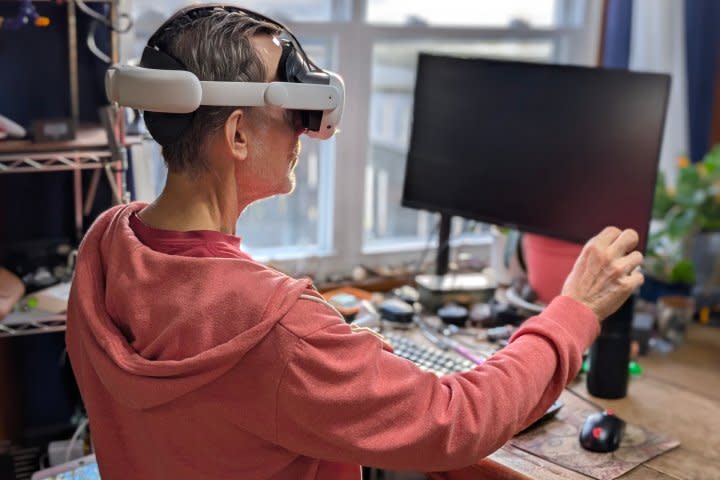 Alan Truly sits in front of a Windows PC and adjusts a virtual screen while wearing a Meta Quest 3 VR headset.