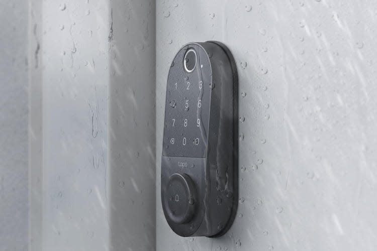 A Tapo smart lock keypad on a white door in the rain.