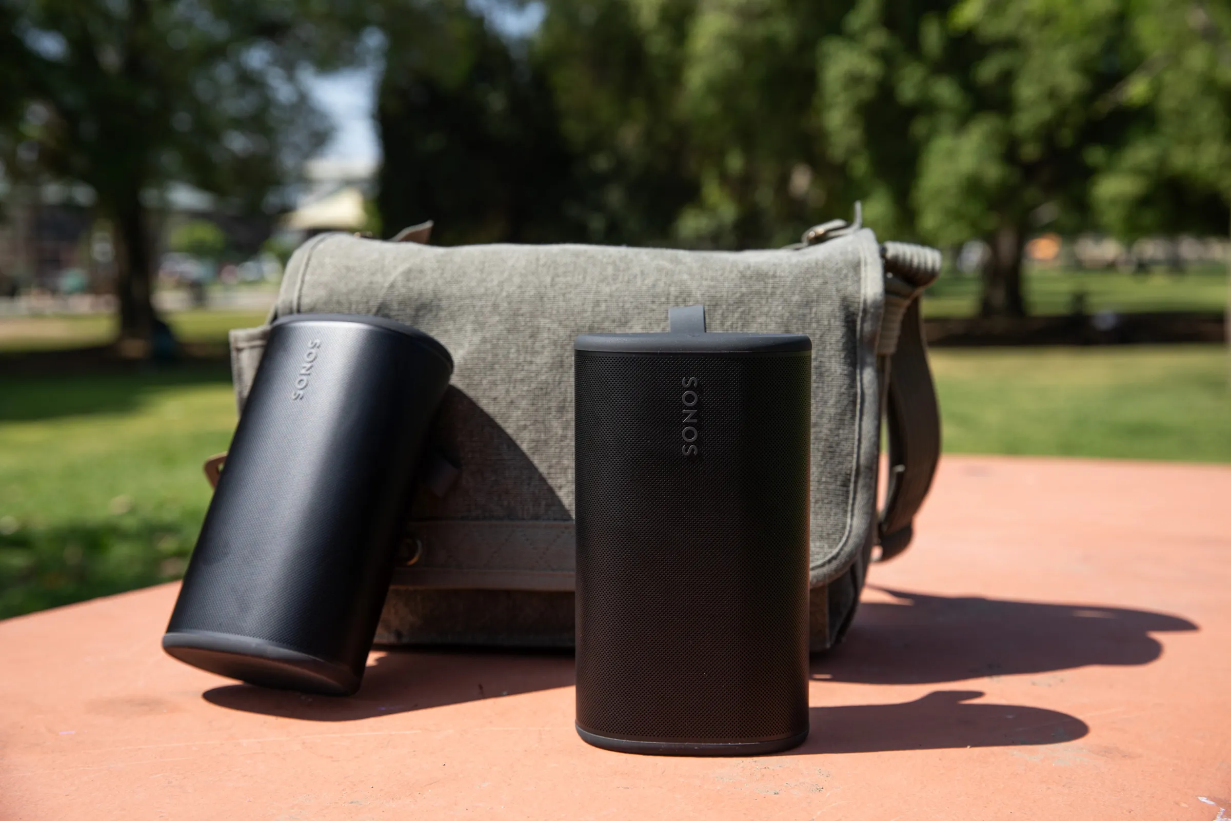 粉红色公园桌子上的两个 Sonos Play 扬声器和鼠尾草绿色袋子